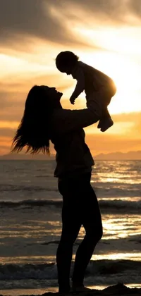 This live wallpaper showcases a serene image of a woman and a child on a beach at sunset