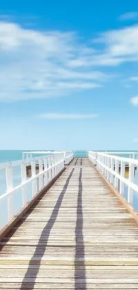 This live wallpaper depicts a wooden pier extending into clear ocean waters, surrounded by a picturesque Australian beach