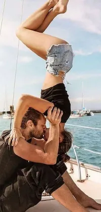 This live phone wallpaper features a stunning image of a man and a woman doing a handstand on a boat