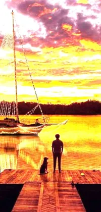 This phone live wallpaper features a man and his dog standing on a dock with a sailboat in the background
