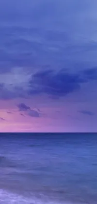 This live wallpaper features a serene beach scene with picturesque rocks set against a stunning purple sky, offering a romantic vibe for your phone