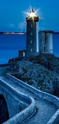 This mobile live wallpaper displays a breathtaking photo of a lighthouse on a rocky shore by the ocean