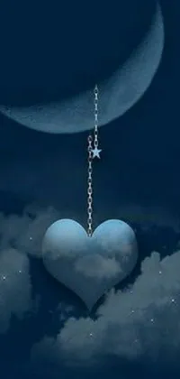 This phone live wallpaper features a beautiful heart suspended from a delicate chain against a soft blue moonlit sky, creating a romantic and captivating image
