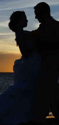 This live wallpaper highlights a beautiful silhouette of a bride and groom on a beach at sunset in Aruba