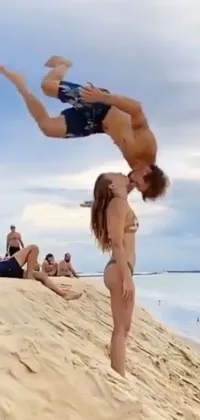 This beach-themed live wallpaper features a playful duo doing a handstand on the sunny shore