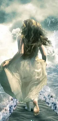 This phone live wallpaper features a stunning image of a woman walking along a beach next to the ocean