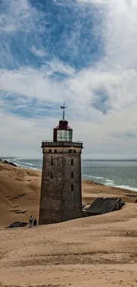This phone live wallpaper features a stunning lighthouse perched atop a sandy beach, with its beam of light shining out into the vast ocean
