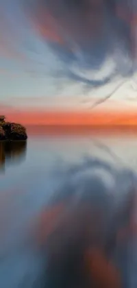 This animated phone wallpaper showcases a serene body of water under a cloudy sky during a colorful sunset with reflections of lava
