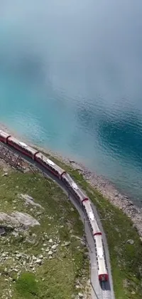 Get mesmerized by this phone live wallpaper featuring a large train on a steel track near a serene body of water