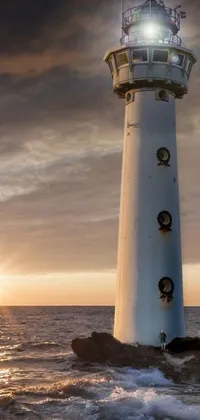 This live phone wallpaper showcases a scenic lighthouse standing on a rock amidst the vast ocean