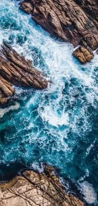 This live wallpaper showcases an aerial view of the ocean and rocks, following a current trend on Pexels