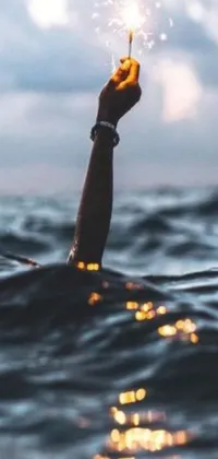 This live wallpaper features a stunning scene of a sparkler illuminating the dark, bloody ocean as it is being held by an anonymous hand