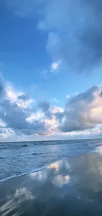 This phone live wallpaper features a stunning scene of a person surfing on a sandy beach with beautiful blue reflections on the water