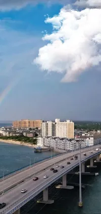 Experience the beauty of a long bridge over a vast body of water with a rainbow in the sky on your phone's live wallpaper