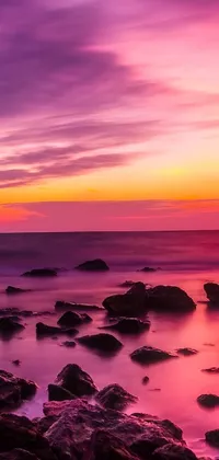 This phone live wallpaper displays a stunning sunset over the ocean with rocks in the foreground