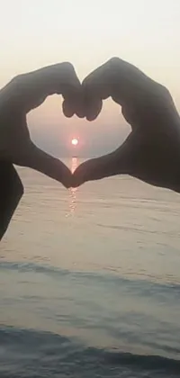 This live wallpaper features a heart shape made with hands in front of a low quality photograph