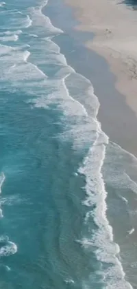 This phone live wallpaper features a stunning view of a large body of water alongside a sandy beach