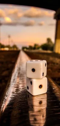 Looking for a unique live wallpaper for your phone that combines realism with artistic flair? Look no further than this design featuring two white dice sitting on a train track at sunset