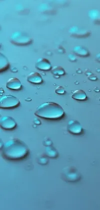 This phone live wallpaper depicts a stunning photo-realistic image of water droplets on a surface, set against a soothing light blue background
