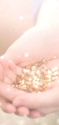 This phone live wallpaper showcases a mesmerizing image of someone holding a handful of gold glitter