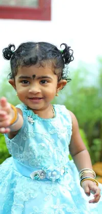 This mobile live wallpaper features a darling image of a little girl wearing a charming blue dress, smiling and giving a thumbs up gesture