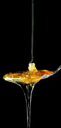 This live phone wallpaper features a close-up photo of a spoon with golden honey on top