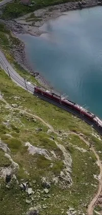 This phone live wallpaper showcases a serene scene of a long train on a steel track near a body of water