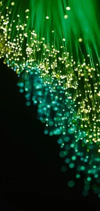 This phone live wallpaper showcases a close-up of a microscopic fiber illuminated with green sparkles in a bioluminescent cyber-garden, surrounded by a network of cables in dreamy bokeh and depth-of-field