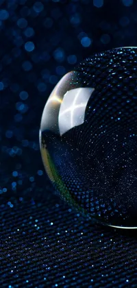 This mesmerizing live wallpaper features a glass ball on a table, captured in macro by Jan Rustem