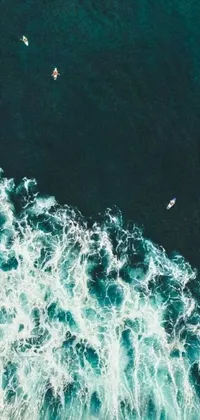 This live wallpaper depicts a stunning scene of surfers riding on a massive wave while viewed from a bird's eye perspective