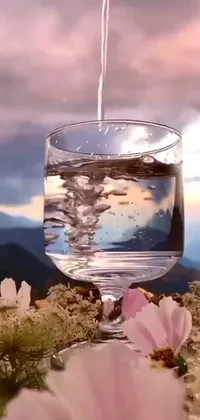 This calming and serene live phone wallpaper features a realistic glass of water sitting on a table, with trickling water creating ripples within the glass