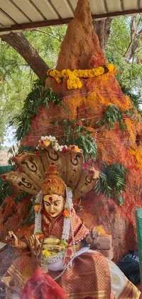 This live wallpaper for your phone showcases an intricately designed statue of a woman sitting under a tree