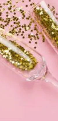 Get ready for some festive fun with this live wallpaper for your phone! You'll be transported into a world of celebration with two champagne flutes filled with golden glitter, set against a soft pink background