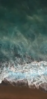 This phone live wallpaper depicts a surfer riding waves on a sandy beach