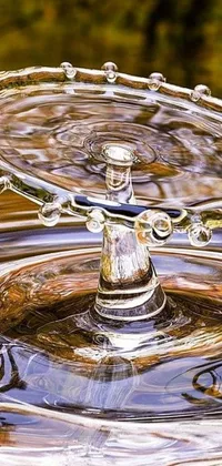 This live phone wallpaper is a stunning art photograph of a water drop in a body of water
