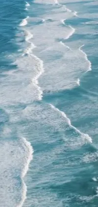 This phone live wallpaper showcases a man riding a surfboard on top of a beach wave