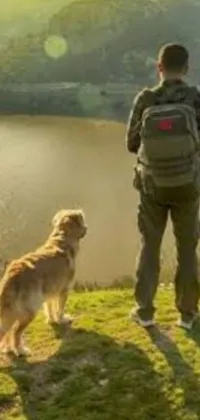Enjoy stunning panoramic views of a tranquil countryside with a man and his faithful dog standing on a hill in this live wallpaper for mobile phones