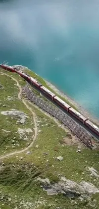 This phone live wallpaper depicts a long train on a steel track near water, surrounded by mountainous terrain