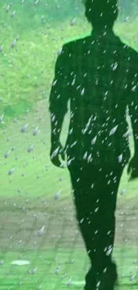 This phone live wallpaper showcases a breathtaking silhouette of a man walking through heavy raindrops