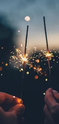 This live wallpaper features two people holding sparklers against a dark purple and blue sky