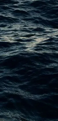 This mobile live wallpaper showcases a captivating close-up of a body of water with waves, set against a deep night sky with a naval backdrop