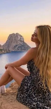 This live wallpaper features a female figure perched atop a cliff overlooking a tranquil ocean