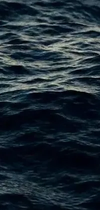 This phone live wallpaper portrays an exquisite close-up view of a serene body of water with waves, encompassing a ship with water on all sides