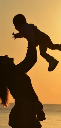 This phone live wallpaper features a breathtaking image of a woman holding a child against a beautiful sunset backdrop