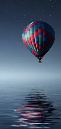 This phone live wallpaper features a stunning digital art of a hot air balloon flying over a serene body of water at night