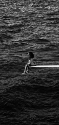 This phone live wallpaper showcases a lone man on a surfboard amidst a serene ocean scene