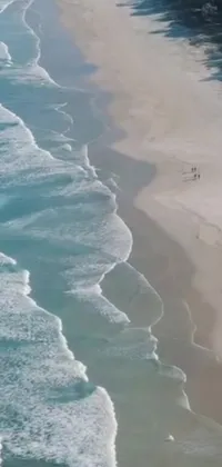 This stunning phone live wallpaper captures a breathtaking aerial shot of a group of people walking along a beautiful beach on the South African coast