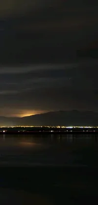 Get mesmerized by the beautiful view of a night-time airplane flying over a vast body of water in this stunning live wallpaper
