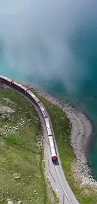 This amazing phone live wallpaper depicts a long train cruising on a steel track near a peaceful body of water in the Swiss Alps