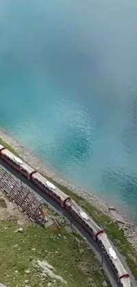 This stunning live wallpaper showcases a long train traveling along a steel track adjacent to a breathtaking body of water, adding an element of visual delight to your phone